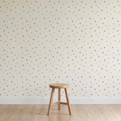 A plain wooden stool sits on a light wood floor before a cream-colored wall decorated with Soaring Hearts Wallpaper featuring subtle, muted bird designs. The minimalist scene appears calm and uncluttered.