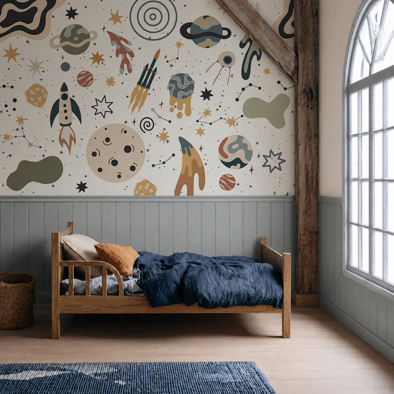 A cozy child’s bedroom with a wooden bed, blue bedding, and the To The Moon Mural featuring rockets, planets, and stars creates an inspiring space-themed atmosphere. Light streams in from a large arched window, making this kids room mural the perfect backdrop for imaginative adventures.