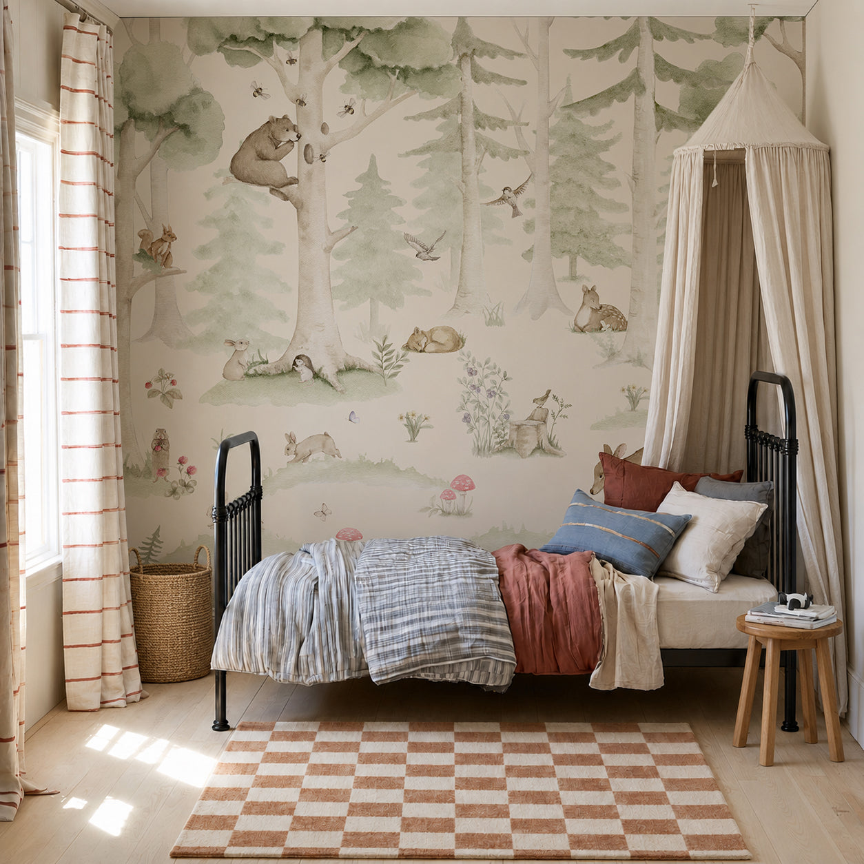 A cozy kids’ bedroom featuring a single black-frame bed, colorful bedding, and a checked rug, with the Woodland Friends Mural showcasing charming woodland creatures. A canopy is draped over the bed, while sunlight pours through a window dressed in striped curtains.
