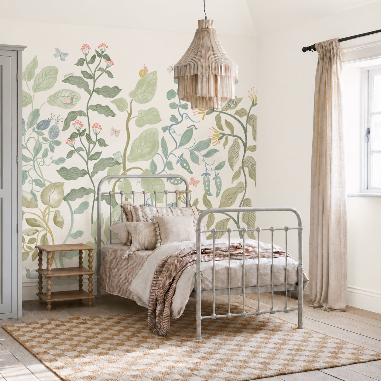 A cozy bedroom featuring a metal bed, beige bedding, a wooden side table, and a checkered rug comes alive with the Secret Garden Mural adorning the wall. A fringe pendant light hangs above, and natural light flows in through a window dressed with beige curtains.