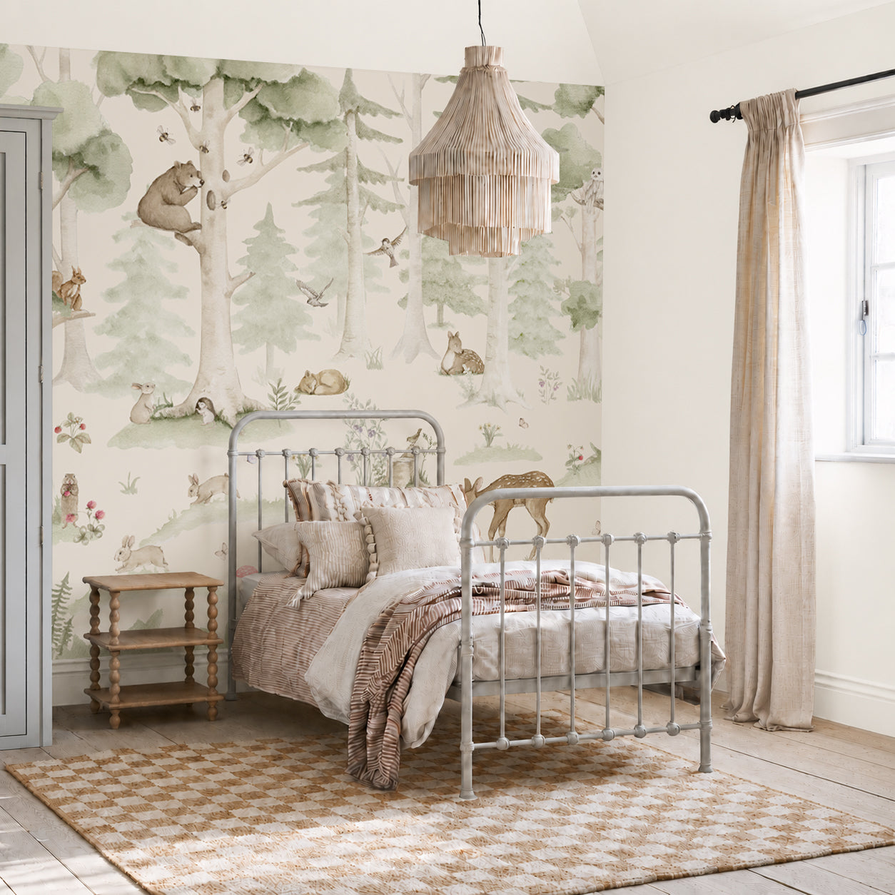 A cozy bedroom featuring a metal bed, neutral bedding, a checkered rug, a wooden side table, and the Woodland Friends Mural adorned with cheerful animals and trees. Light streams in through a window dressed with beige curtains.