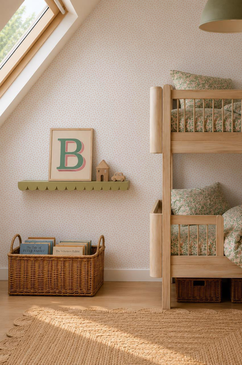 Cozy children’s bedroom with wooden bunk beds, a wicker basket, a green shelf holding decor items, and a framed letter “B” displayed on whimsical Sprinkle Wallpaper in pink under a skylight.