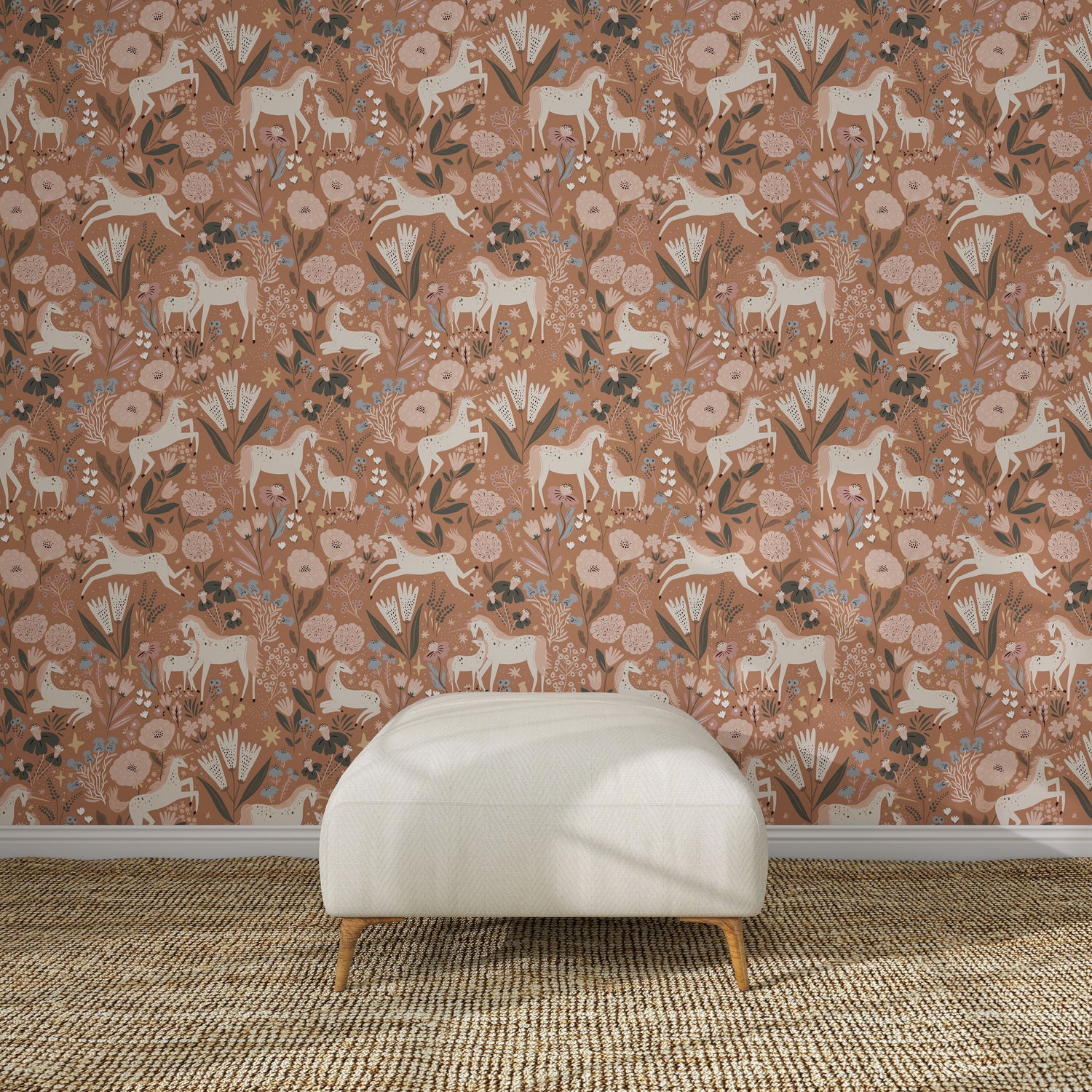 The wall features Unicorn Meadow Wallpaper Toffee Rose, with white goats, flowers, and leaves in earthy tones, behind a modern white upholstered bench placed on a textured woven rug.