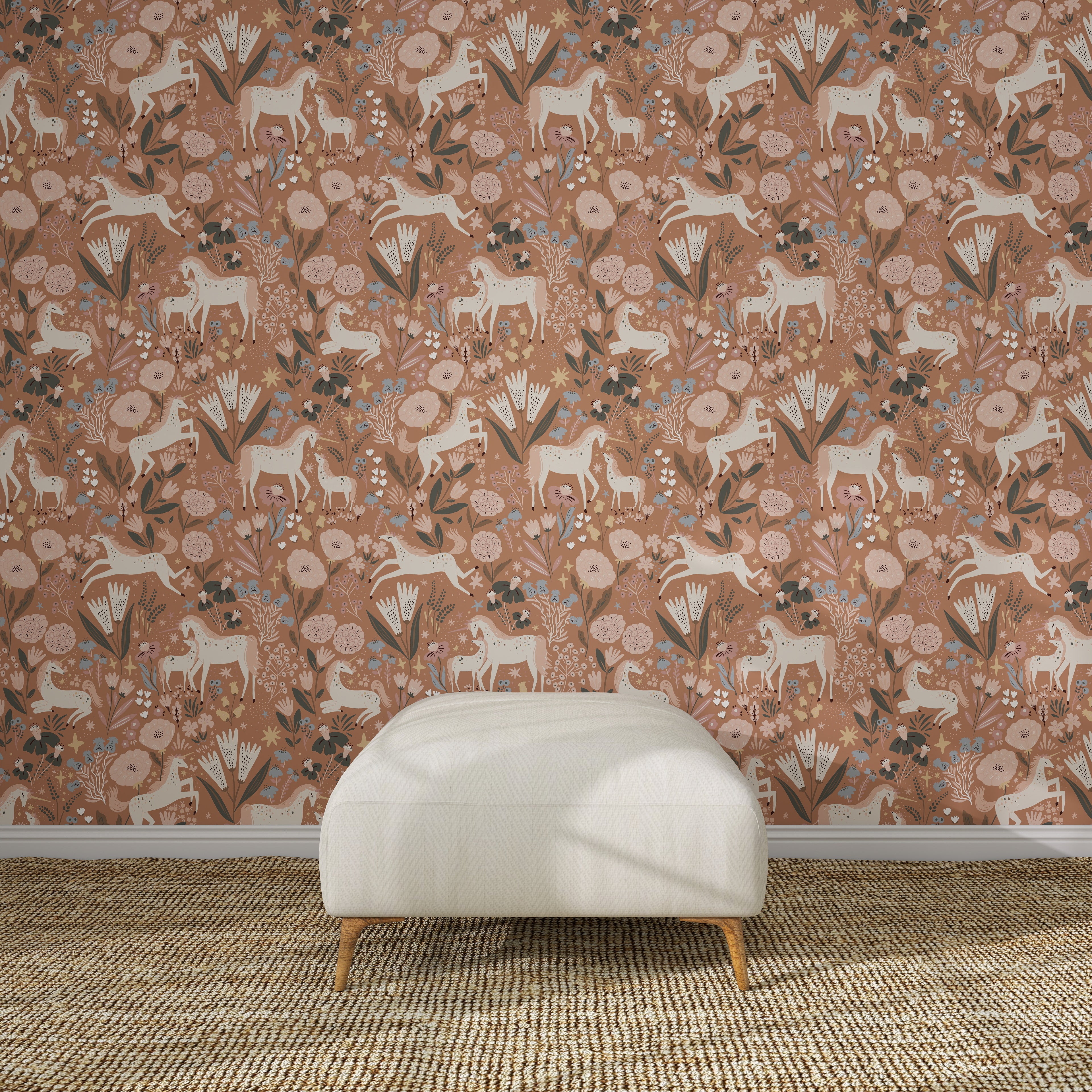 The wall features Unicorn Meadow Wallpaper Toffee Rose, with white goats, flowers, and leaves in earthy tones, behind a modern white upholstered bench placed on a textured woven rug.