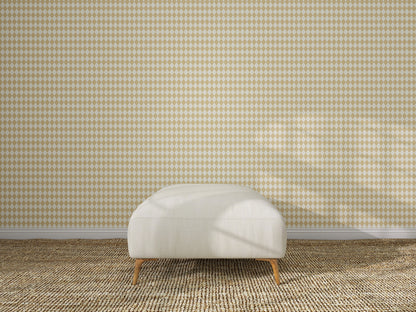 A white upholstered ottoman with wooden legs sits on a textured beige carpet in front of Diamond Dancer Wallpaper, Yellow. Sunlight casts soft shadows across the scene, highlighting the geometric diamond pattern.