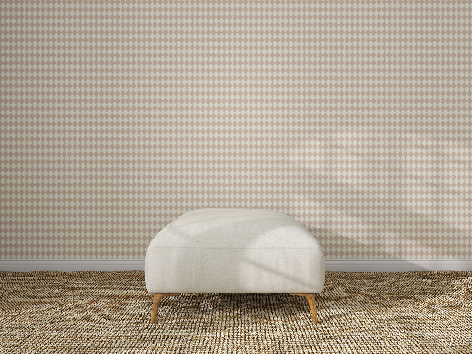 A beige ottoman sits on a woven carpet in front of a wall featuring the Diamond Dancer Wallpaper Sample in Rose. The empty, well-lit room has soft shadows on the wall and floor.