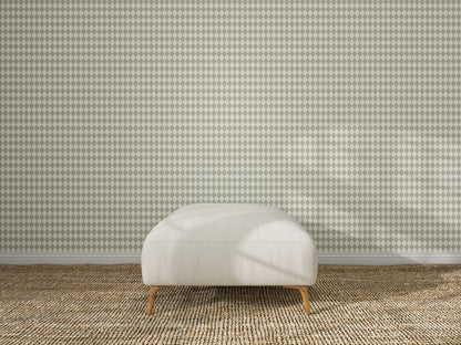 A cream-colored ottoman with wooden legs sits on a woven beige carpet, centered in front of a wall covered with Diamond Dancer Wallpaper, Green.