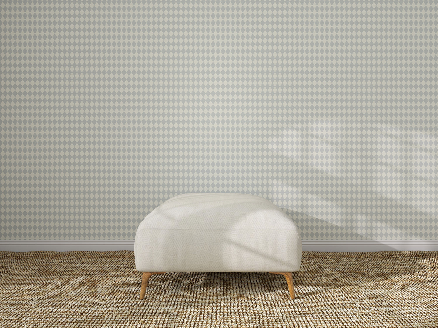 A white ottoman rests on a textured beige carpet in front of a wall adorned with Diamond Dancer Wallpaper in Blue, its subtle geometric pattern highlighted by sunlight casting gentle shadows across the floor and wall.