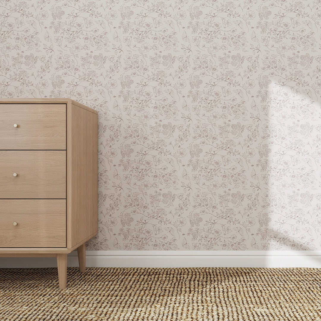 A light wooden dresser with three drawers stands on a woven rug next to the Sunlit Meadow Wallpaper Repeat Pattern, its exceptional quality highlighted by sunlight creating a bright patch near the corner.