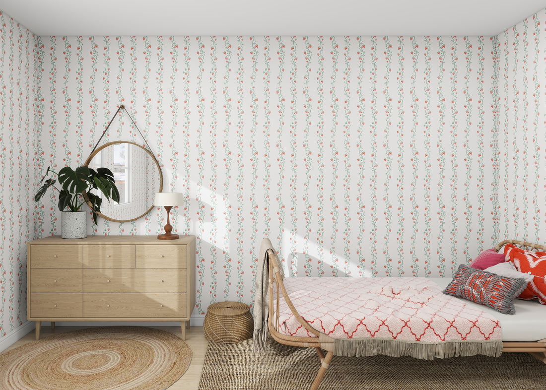 A cozy bedroom features the Strawberry Stripes Wallpaper Repeat Pattern by munks and me, enhancing the wooden bed with pink and orange bedding. A round mirror and plant grace a wooden dresser, while a wicker basket and woven rug bring natural texture, as sunlight beams in from the right.