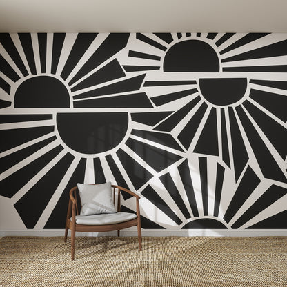 A modern room features the striking Sunbeams Wallpaper Repeat Pattern | Charcoal with geometric black and white stylized suns and rays, alongside a wooden chair with a cushion and a woven rug on the floor.