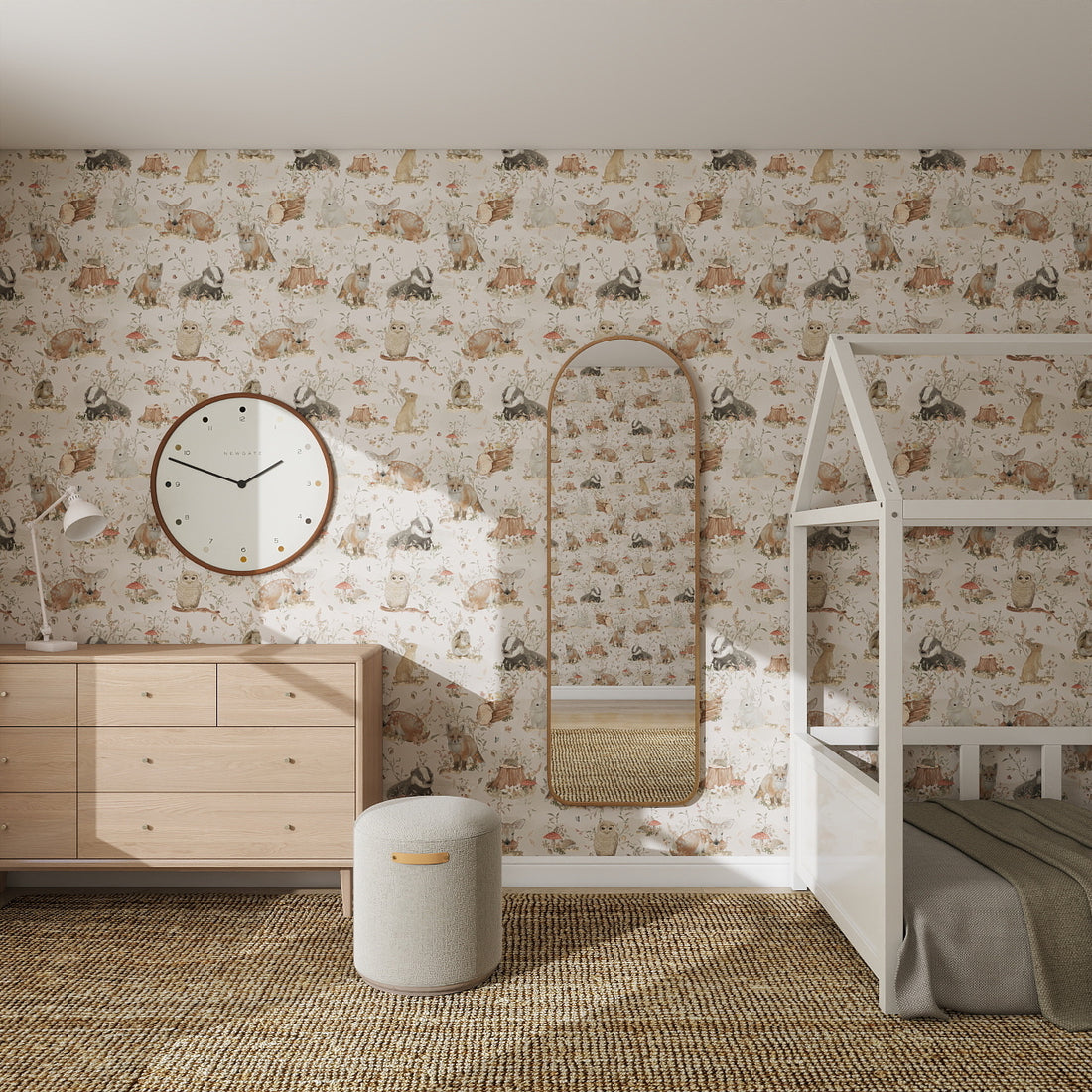 A cozy children’s bedroom with a playful Woodland Wonder Repeat Pattern wallpaper, a wooden dresser, wall clock, arched mirror, small ottoman, and a white house-shaped bed on a woven rug.