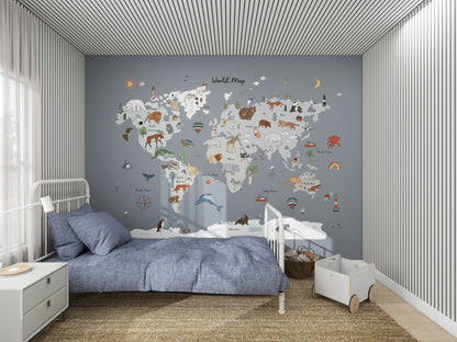 This childrens bedroom boasts a World Map Wallpaper Mural | Blue by munks and me, featuring cartoon animals and landmarks ideal for young geography fans. A cozy bed with blue bedding sits beside a white bedside table on the left, while a small wagon brings playfulness to the right side.