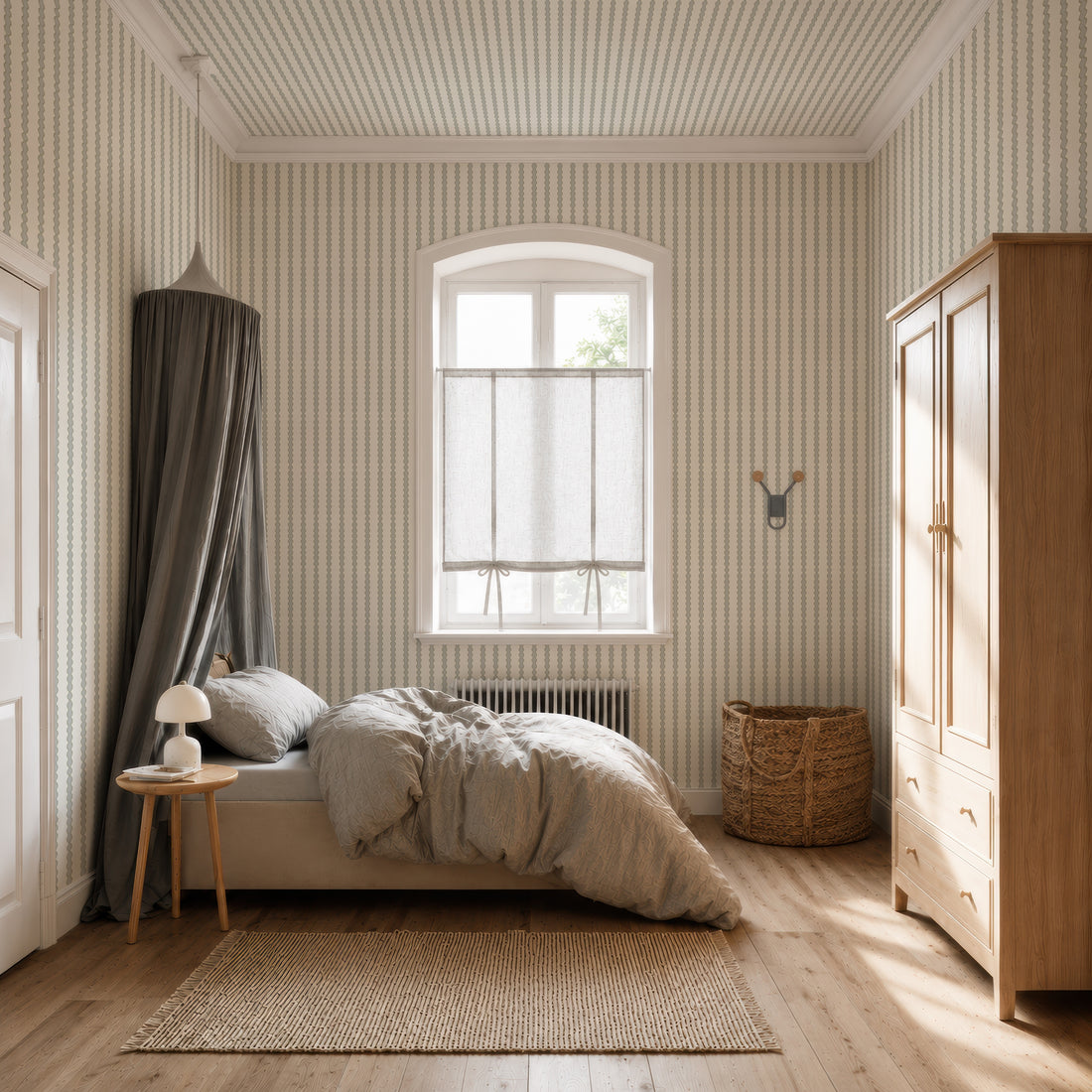 Cozy bedroom with a canopy bed, light bedding, small round side table and lamp, wicker basket, wooden wardrobe, and Little Abacus Stripe Wallpaper in Blue and Green. Sunlight streams through a window with sheer curtains.