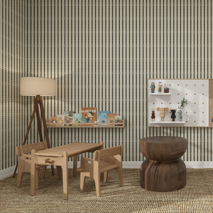 A cozy children’s playroom with light wooden furniture, small table and chairs, tripod lamp, books on a wall shelf, and a calming atmosphere enhanced by nursery decor and Little Abacus Stripe Forest bold vertical stripe walls.
