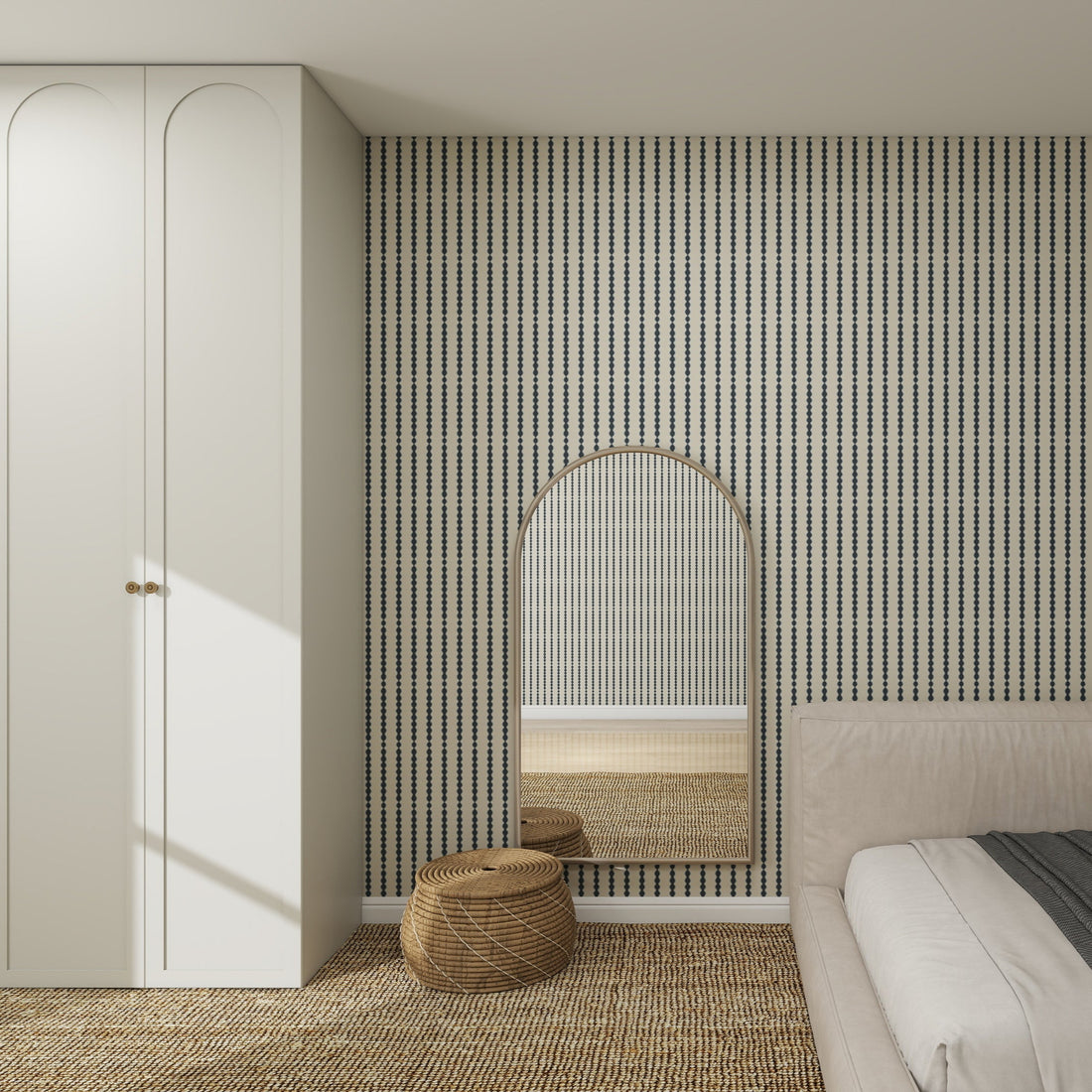 A modern bedroom features Little Abacus Stripe Denim Wallpaper, a large arched mirror, a woven round pouf, a white wardrobe, and part of a beige bed with textured carpet on the floor.