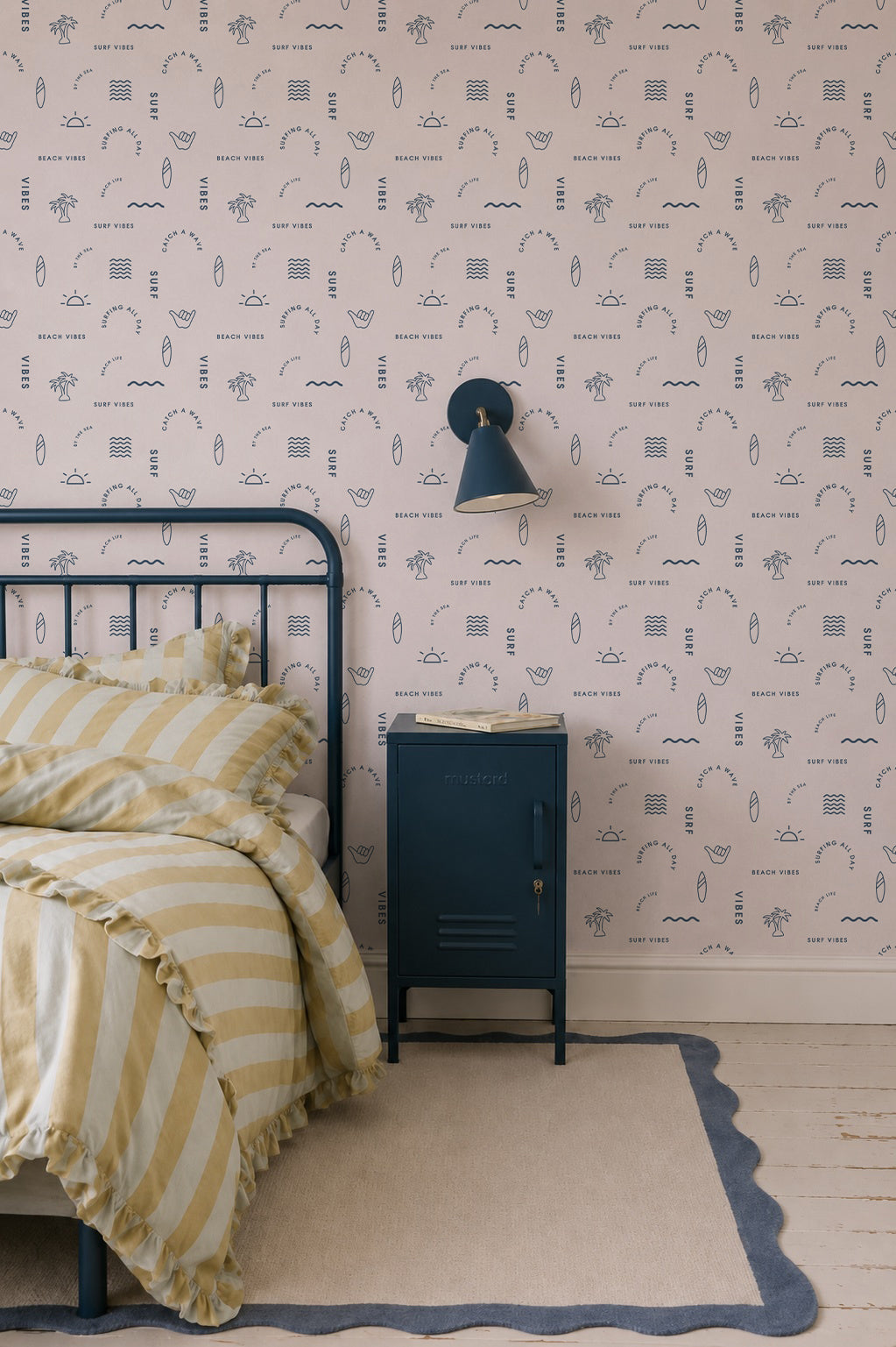A cozy bedroom with a metal bed frame, yellow and white striped bedding, a blue nightstand, and Beach Vibes Wallpaper, Blue featuring abstract patterns for a relaxed coastal feel.