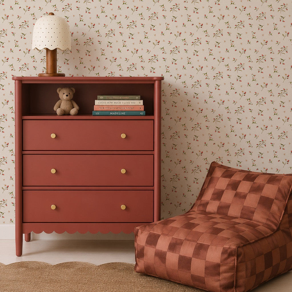 A rust-colored dresser with books, a teddy bear, and a polka-dot lamp sits beside a brown checked lounge chair against Berry and Bramble Wallpaper in a cozy room.