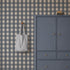 A grey cabinet with a toy car on top and a striped tote bag hanging on a Large Check Wallpaper, Deep Blue wall.