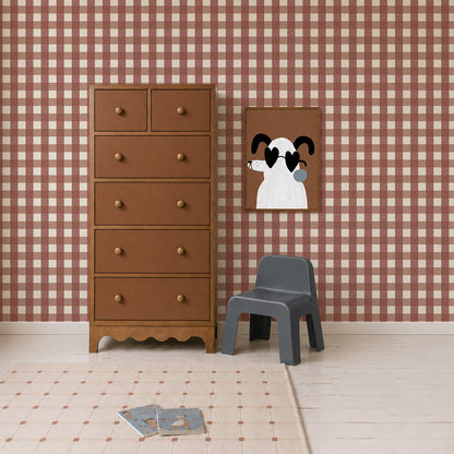 A wooden chest of drawers, a small grey chair, and a framed print of a dog wearing heart-shaped sunglasses, set against Large Check Wallpaper, Red.