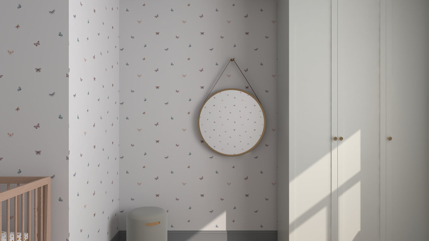 A minimalist corner features munks and mes Bibi Butterflies Wallpaper with hand-drawn details. A round mirror decorates the wall, complemented by a wooden crib and round storage basket. Soft sunlight casts shadows on the wardrobes light-colored doors.