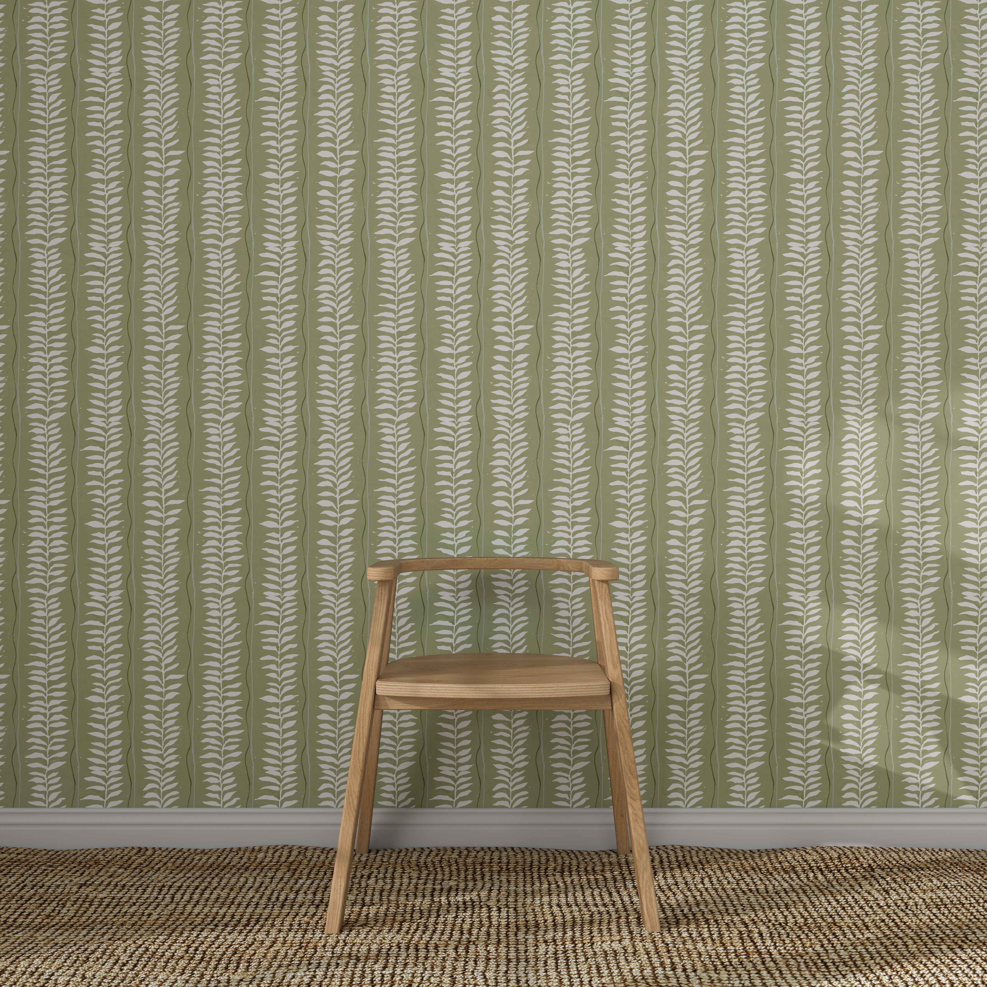 A wooden chair with a simple design sits on a woven rug in front of Meadow Leaf Stripe Wallpaper, Sage, its white botanical stripes adding charm to the cozy space.
