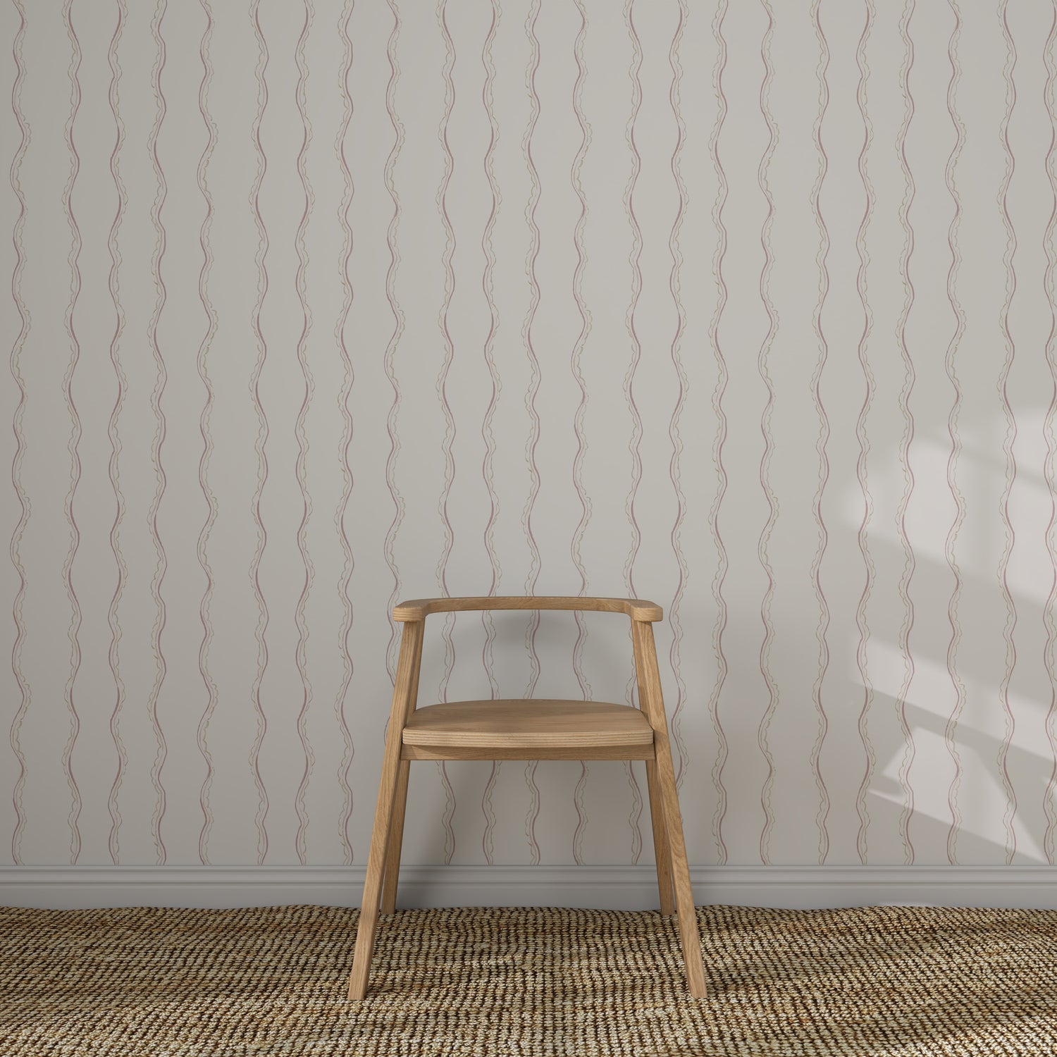 A simple wooden chair sits against a wall adorned with Ribbon Stripe Wallpaper in Rose. The floor features a textured woven rug, and gentle light casts a shadow, creating elegant children&