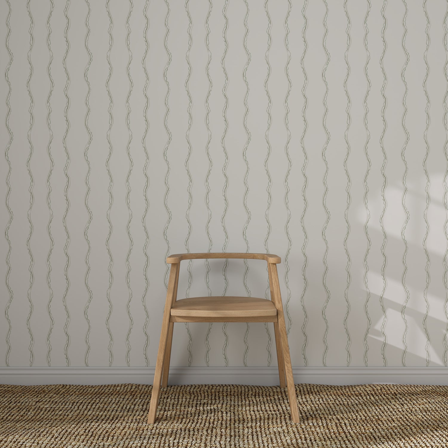 A light wooden chair with a curved backrest sits on a woven rug before a white wall featuring Ribbon Stripe Wallpaper in Sage. Sunlight casts partial shadows, creating an elegant children&