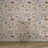 A wooden chair rests on a woven rug in front of the colourful Little Wanderers Wallpaper Sample, which features playful illustrated animals like zebras, cheetahs, tigers, and horses among whimsical trees and flowers.