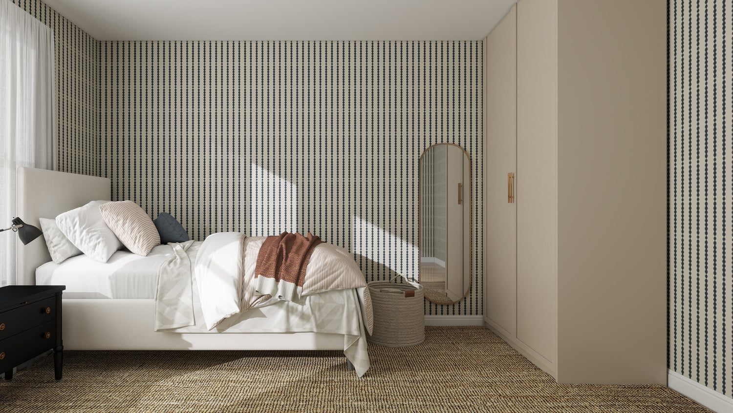 A modern bedroom features a bed with white linens, a black nightstand and lamp, full-length mirror, woven basket, beige wardrobes, and quality Little Abacus Stripe Denim Wallpaper. Natural light streams through the window.