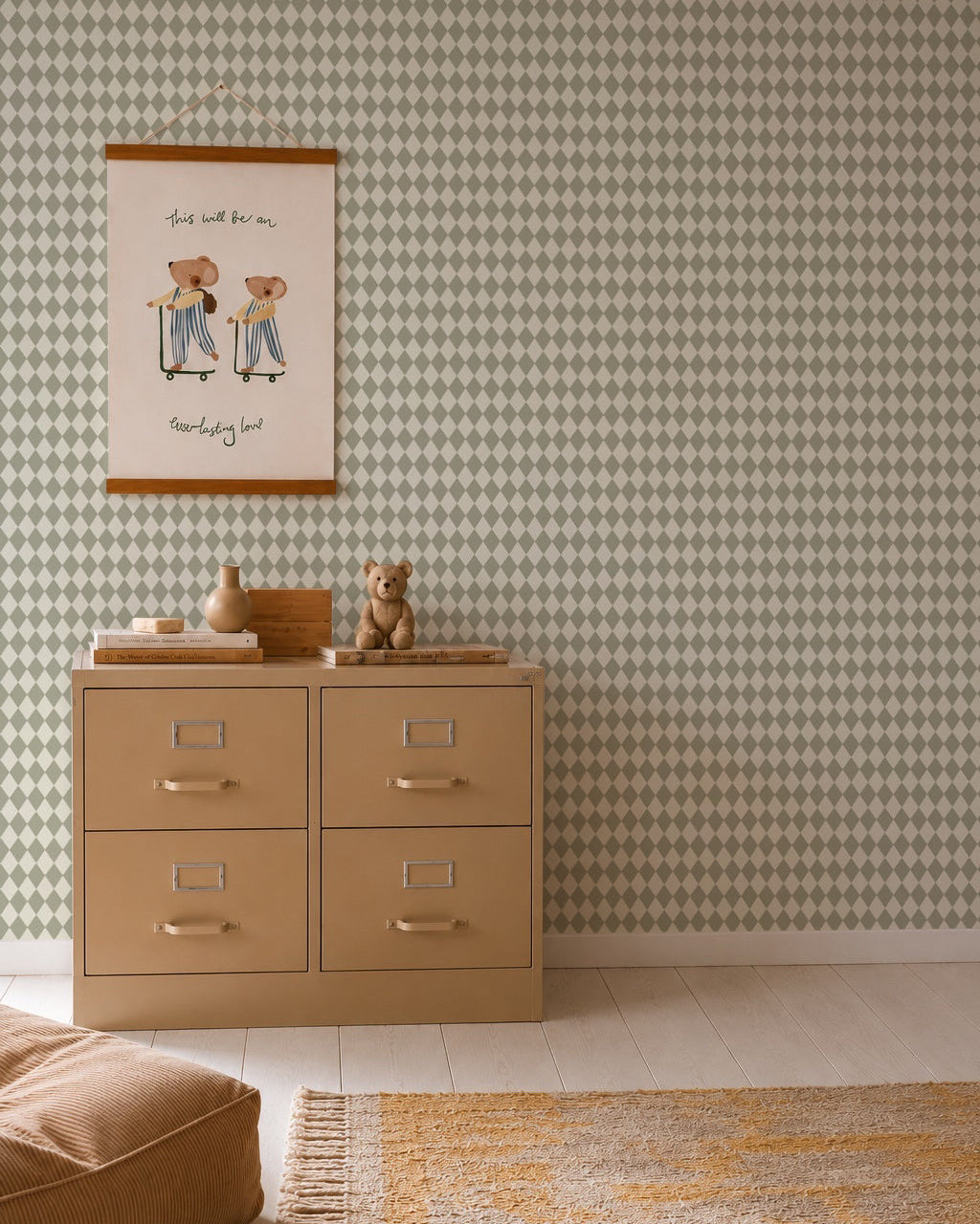 A beige dresser with silver handles stands against Diamond Dancer Wallpaper, Green. On top are a teddy bear and decorative vases. Above hangs a framed illustration of two bears in stripes. A rug rests on the light wood floor.