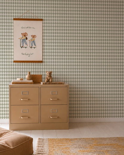 A beige dresser with silver handles stands against Diamond Dancer Wallpaper, Green. On top are a teddy bear and decorative vases. Above hangs a framed illustration of two bears in stripes. A rug rests on the light wood floor.