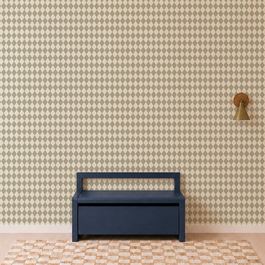 A navy blue bench sits against a wall adorned with Diamond Dancer Wallpaper in green, featuring a geometric diamond pattern; a brass wall sconce is mounted to the right, and a geometric patterned rug is on the floor.