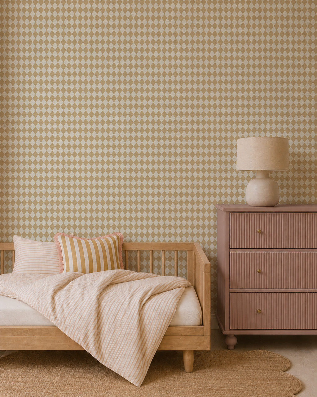 A cozy bedroom with a wooden bed, beige-striped bedding and pillows, a pinkish-brown dresser topped with a round lamp, a scalloped jute rug, and striking Diamond Dancer Wallpaper in yellow.