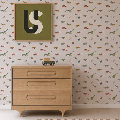 Light wooden dresser with three drawers, a small toy car on top, Dino Discovery Wallpaper featuring playful dinosaurs for young adventurers, and a framed abstract art piece with letters U and S on the wall above.