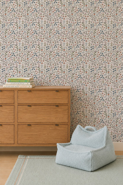 A wooden dresser topped with books stands next to a light blue bean bag chair on a green rug, set against a wall decorated with Ditsy Blooms Wallpaper.