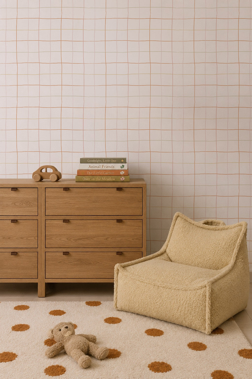 Minimalist nursery with a wooden dresser, children’s books, toy phone, beige fuzzy chair, polka dot rug featuring a plush teddy bear, and walls adorned with Doodle Grid Wallpaper—a subtle repeat pattern ideal for modern interiors.