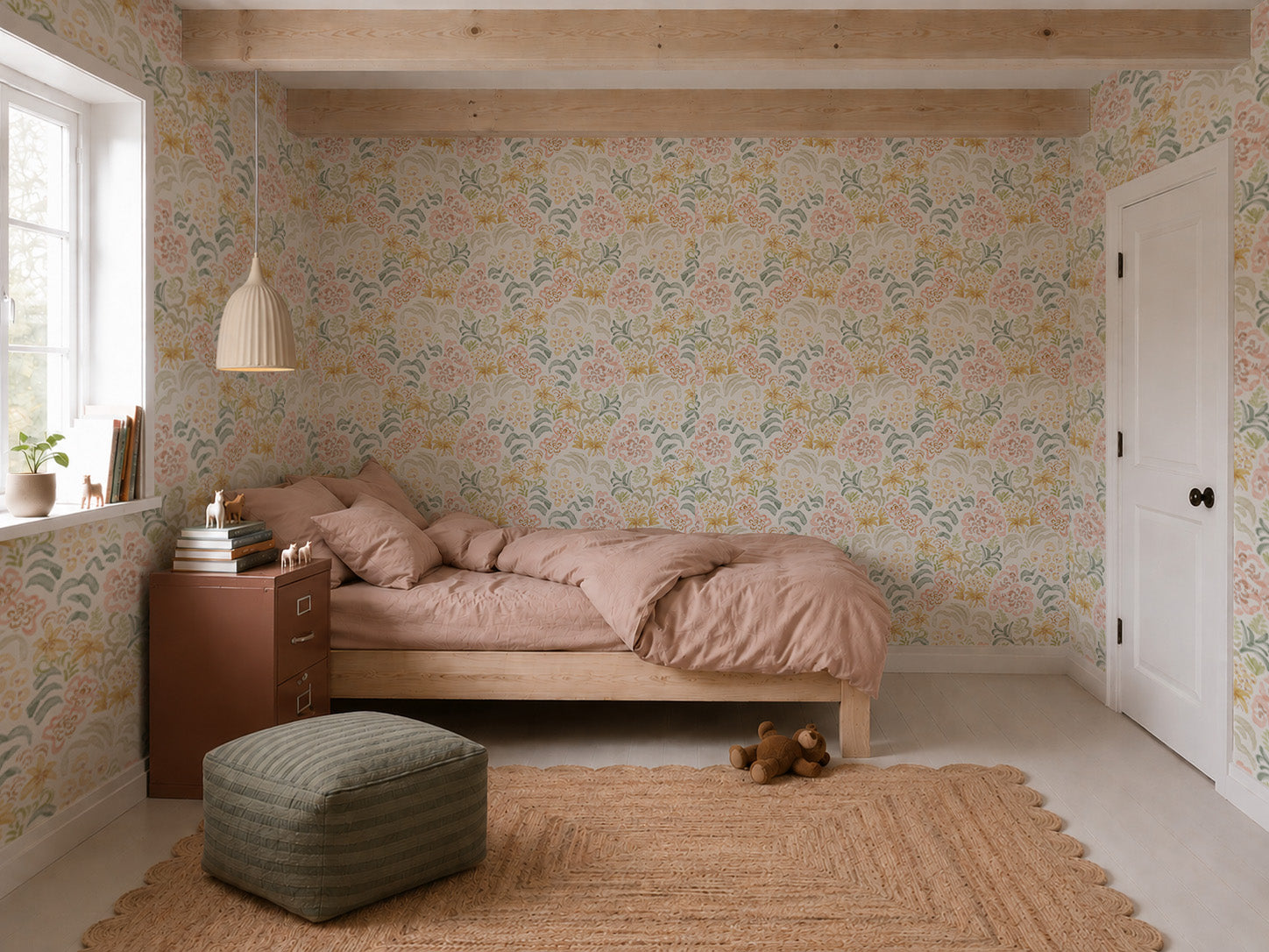 Cozy bedroom featuring Floret Dreamscape Wallpaper in pastel florals, a wooden bed with pink bedding, a brown nightstand, a hanging lamp, window with plants, a jute rug, green ottoman, and a teddy bear on the floor.