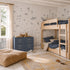 Children’s bedroom with wooden bunk beds, a blue dresser, tan pouf, and a rug. The walls feature the Fish Tank Mural in blue, filled with sea creatures like fish, jellyfish, and underwater plants. Sunlight streams in from a window with beige curtains.