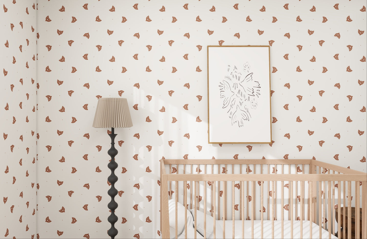 In the nursery, the walls feature Flutter Sky Wallpaper Repeat Mocha by munks and me. A crib with light wood slats and white bedding is paired with a framed abstract line drawing above. Nearby, a tall wavy black floor lamp with a beige pleated shade enhances the warmth of the mocha-toned decor.