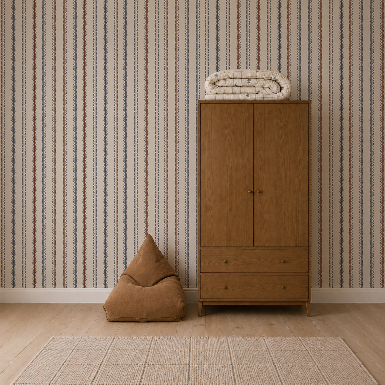 A brown wardrobe with a folded blanket on top stands next to a tan bean bag on a light wooden floor, complemented by Folk Scallop Stripe Wallpaper in Chambray &amp; Mocha and a beige rug in the room.