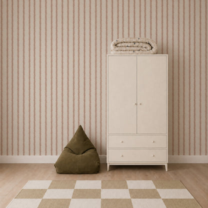 A minimalist room featuring Folk Scallop Stripe Wallpaper in Rose &amp; Mocha, a white wardrobe with folded bedding on top, a green bean bag, and a beige-and-white checkered rug on a wooden floor.