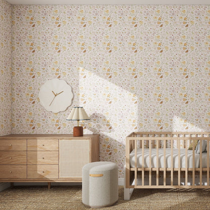 A nursery with Garden Symphony Wallpaper Repeat Pattern, a light wood crib, a matching dresser with lamp, a decorative wall clock, and a round cushioned stool on a woven rug. Sunlight streams in from an unseen window.
