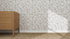A wooden dresser stands on a textured carpet beside a white wall decorated with whimsical art and Hallie Leopard Print Wallpaper Repeat Pattern in Charcoal. Sunlight casts shadows across the floor, highlighting the room’s playful charm.