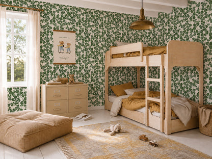 Children’s bedroom featuring How Lucky We Are Clovers Wallpaper, a wooden bunk bed, beige dresser, soft pouf, teddy bear on a rug, and a window with sheer curtains allowing in natural light.