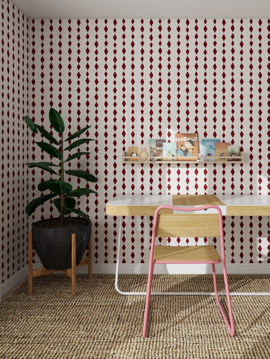 A modern study room featuring Jolly Jester Wallpaper Repeat Cherry sample, a wooden desk and chair, shelves with books and decor, a large potted plant, round-top mirror, and a woven rug adding colour to the floor.