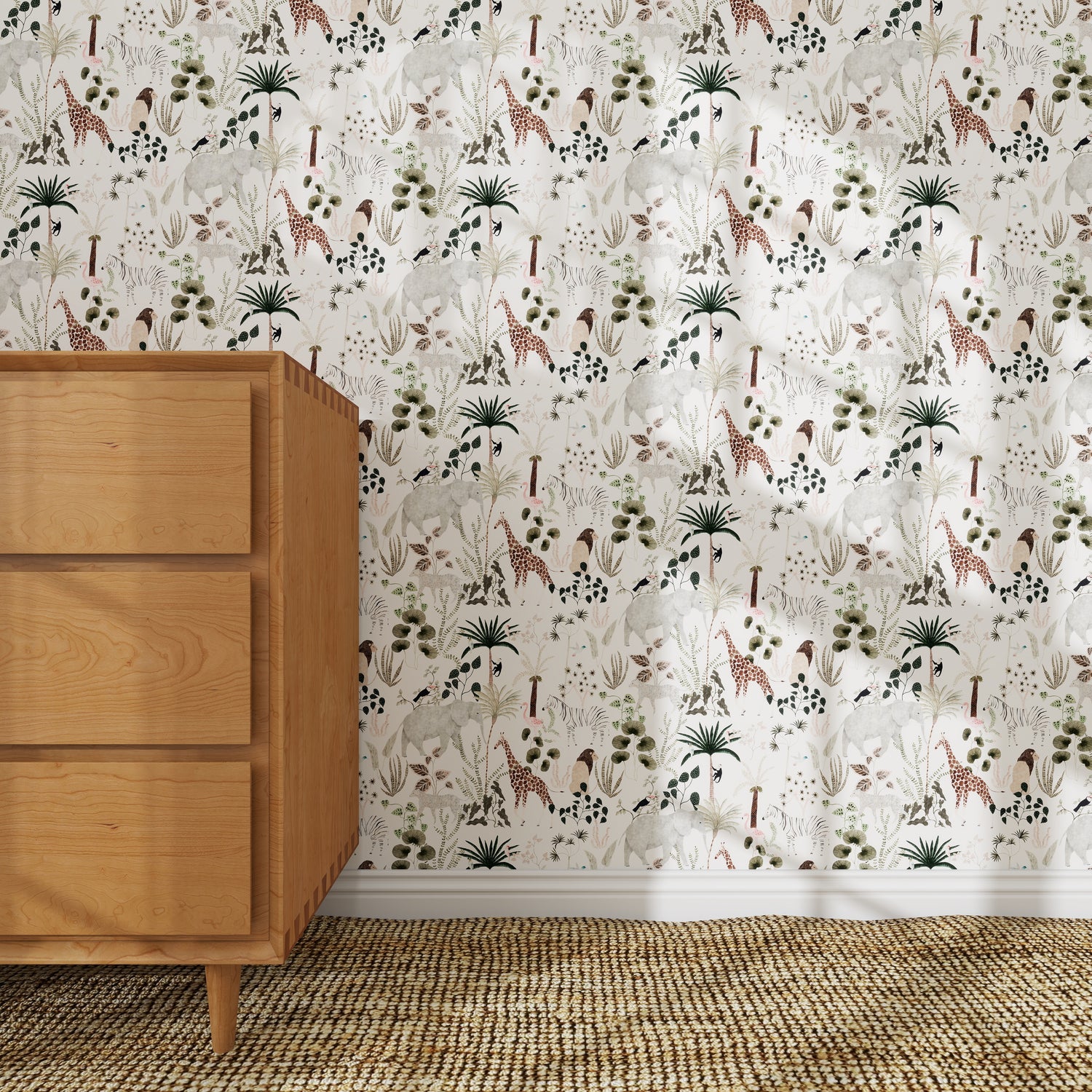 A wooden dresser sits on a textured woven rug. Behind it, the Jungle Dreams Wallpaper Repeat Pattern displays playful giraffes, elephants, palm trees, and plants in soft neutral tones.