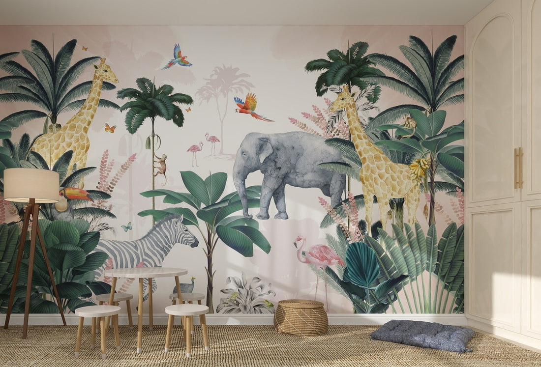 The Jungle Wallpaper Mural | Pink decorates a kids’ room with vibrant illustrations of giraffes, elephant, zebra, parrots, and flamingos amidst lush greenery. Small tables and chairs are placed in front of the playful mural.