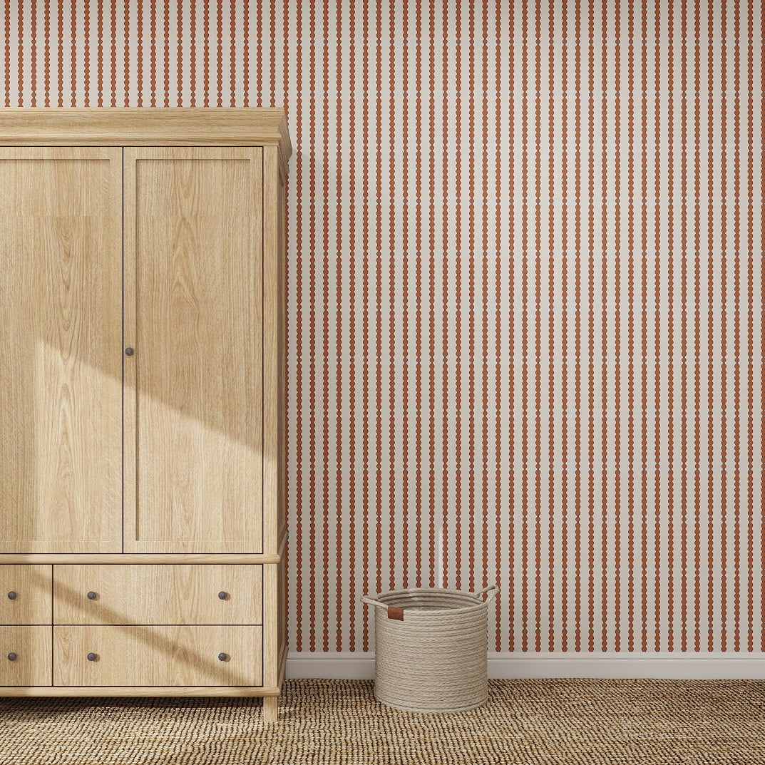 A light wood wardrobe stands on a woven rug beside a beige basket, set against a wall with Little Abacus Stripe Red and Blue nursery wallpaper. Sunlight casts a shadow on the wardrobe.