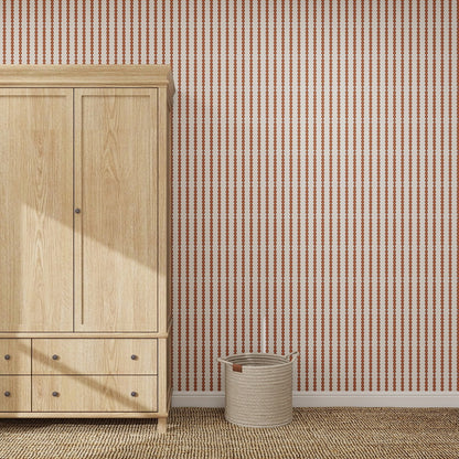 A light wood wardrobe stands on a woven rug beside a beige basket, set against a wall with Little Abacus Stripe Red and Blue nursery wallpaper. Sunlight casts a shadow on the wardrobe.